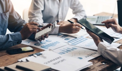 three faceless business people around a desk with charts and calculators used on a blog about how to get funding for a business