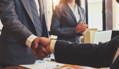 business people shaking hands over a desk | MGI