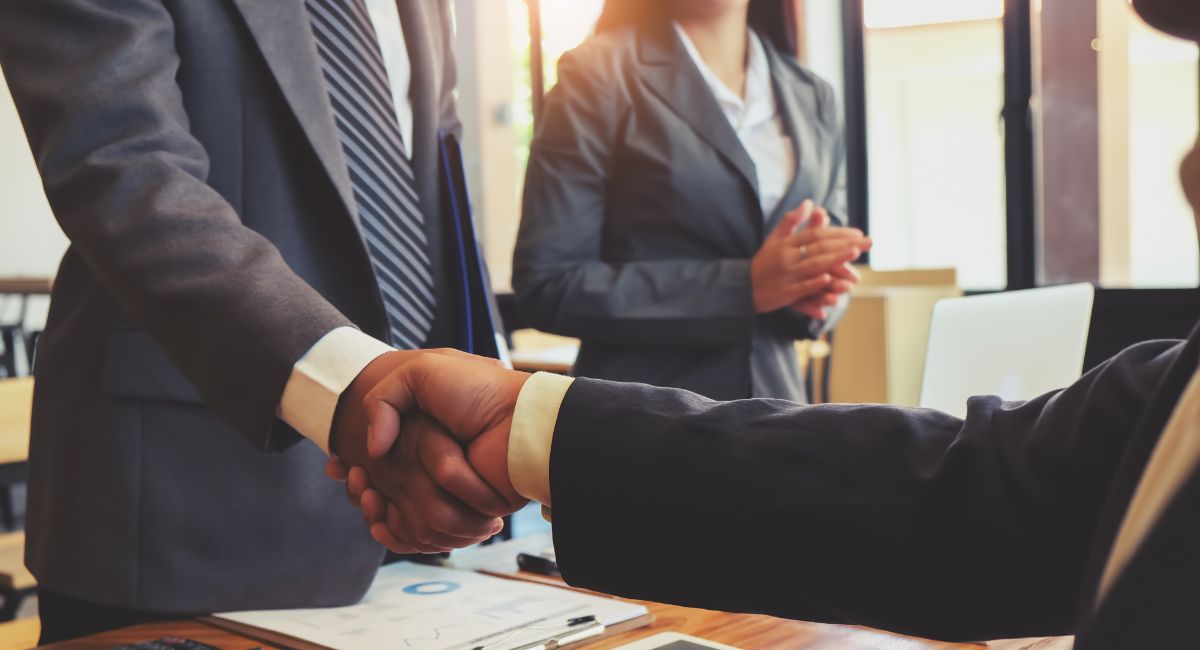 business people shaking hands over a desk | MGI