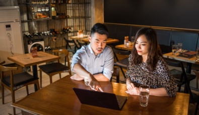 2 business owners discussing federal budget pointing at laptop