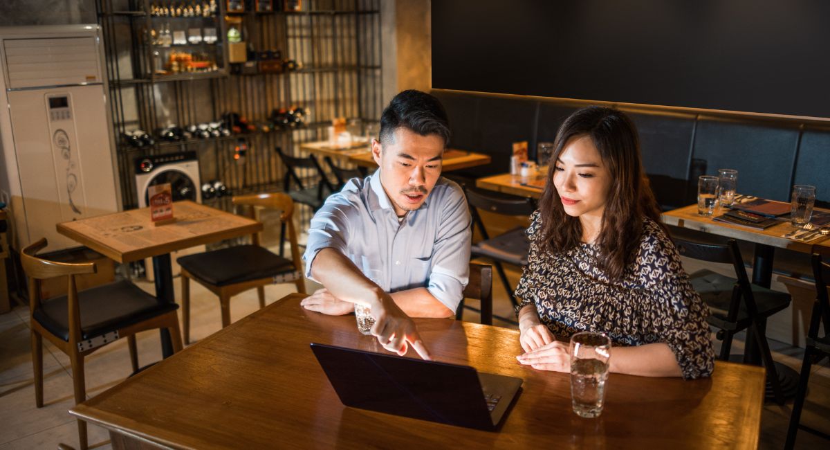 2 business owners discussing federal budget pointing at laptop