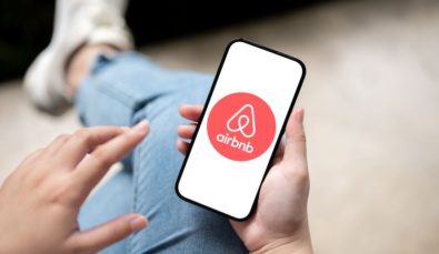 hands holding mobile phone with airbnb logo pictured