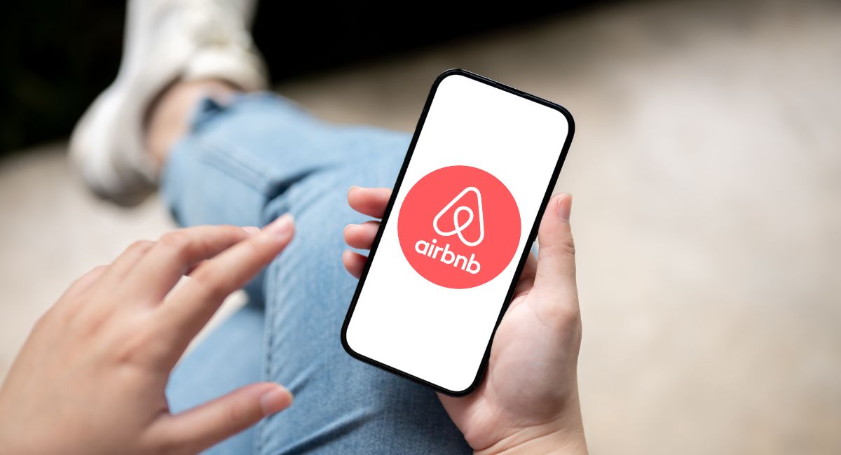 hands holding mobile phone with airbnb logo pictured