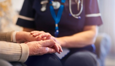 aged care nurses hands holding those of an elderly patient.