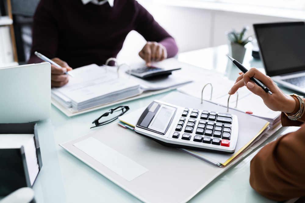 Close Up,of,two,businesspeople,calculating,financial,statement,at,desk