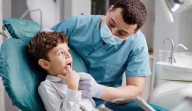a Paediatric Dentist examining a small boy's teeth used on a blog about pcg2021/1 and wealth structuring for dentists