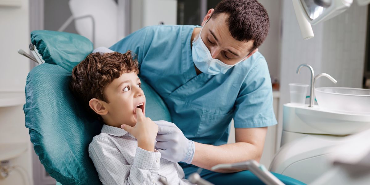 a Paediatric Dentist examining a small boy's teeth used on a blog about pcg2021/1 and wealth structuring for dentists